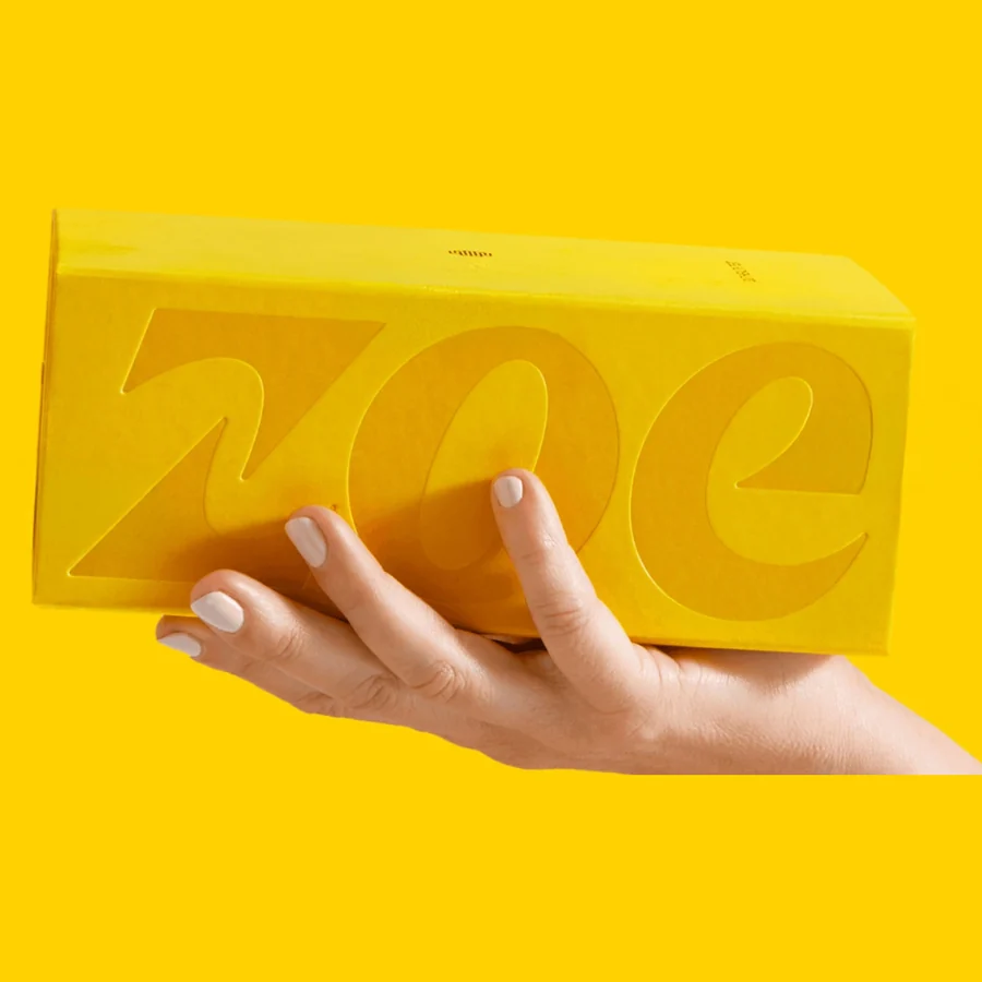 The ZOE gut health test kit box held open in two hands, showing the sample collection disc inside